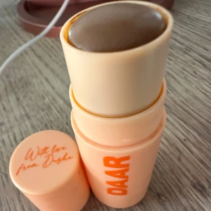 Bronzer Cinnamon Roll från DAAR Använd 1 tillfälle   - Säljer en bronzer i nyansen Cinnamon Roll från DAAR. Den kommer i en praktisk stickform som gör den enkel att applicera. Perfekt för att ge ansiktet en solkysst look. Förpackningen är i en ljus orange färg med texten 'With love from Dasha' på locket.,Använt 1 tillfälle fint bevarad 