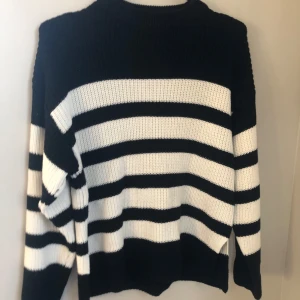 Svartvit randig stickad tröja - Säljer en svartvit randig stickad tröja med långa ärmar. Perfekt för kyligare dagar med sin mysiga och bekväma oversize passform. Tröjan har en klassisk design som passar till många olika stilar.  Den har även slit så både sidorna . Kommer inte till användning ❤️ pris kan diskuteras 