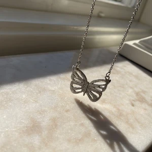 Silverfärgat halsband med fjärilshänge - Elegant silverfärgat halsband med ett detaljerat fjärilshänge. Kedjan är tunn och smidig, vilket ger en stilren look.💓 Perfekt för att lägga till en touch av elegans till din outfit. Skriv till mig ifall ni undrar något💓