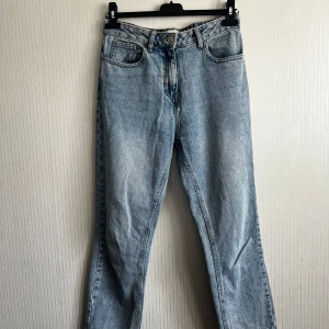 Blå jeans från Next - Snygga blå jeans från Next i en straight modell med hög midja. Perfekta för en avslappnad stil. Klassisk femficksdesign och knappgylf.