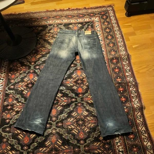 Bootcut jeans Armani Jeans - Snygga mörkblå jeans från Armani Jeans med en klassisk femficksdesign. De har en tvättad look och kontrasterande sömmar. Uppsydda nedtill, går att sprätta upp och göra några cm längre.
