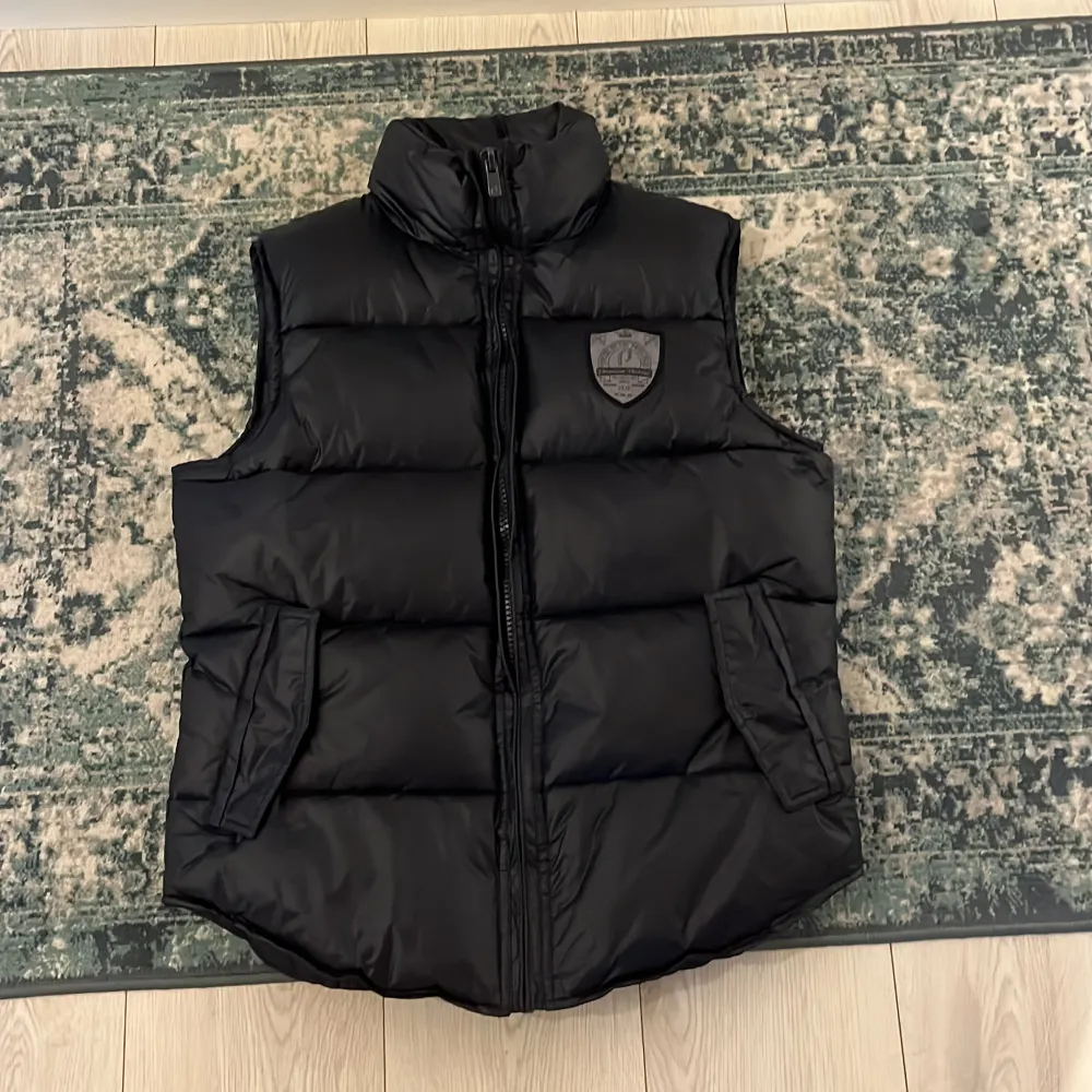 Snygg svart dunväst från Jack & Jones med dragkedja och en cool logga på bröstet. Fint skick utan defekter, säljs inte längre och är en vintage ”piece”. Storlek s men passar M. Hör av er vid frågor! 🍾. Takit.