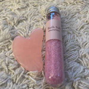 Rosa Gua Sha och badsalt med grapefrukt - Säljer en vacker rosa Gua Sha-sten tillsammans med ett rör av badsalt med grapefruktdoft. Perfekt för en avkopplande spa-dag hemma. Gua Sha-stenen är slät och formad för ansiktsmassage.