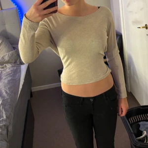 Beige croppad tröja med knyt - Snygg beige croppad tröja med långa ärmar och knyt i midjan. Perfekt för en stilren och avslappnad look.