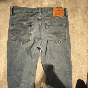 Levis 505 jeans - Klassiska Levis 505 jeans i blå denim. De har en rak passform och är tillverkade i slitstarkt jeanstyg. Perfekta för en avslappnad stil.