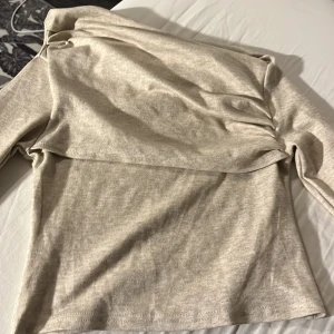 Beige ribbad tröja - Säljer en stilren beige ribbad tröja med långärmad design. Perfekt för en avslappnad look. Tröjan har en mjuk och bekväm känsla, idealisk för kyligare dagar.