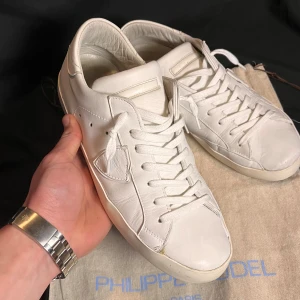 Vita sneakers från Philippe Model - Snygga vita sneakers från Philippe Model. De har en klassisk design med snörning och en diskret logga på sidan. Perfekta för en stilren look. Dustbag ingår! Passar även 44