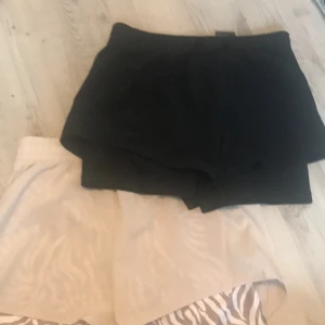 Shorts från Move - Två par shorts från Move. Ett par är svarta och det andra är beige med ett subtilt zebramönster. Perfekta för en avslappnad stil. De har en elastisk midja för extra komfort.