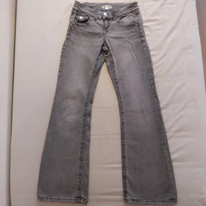 Grå jeansbyxor från Gina Tricot - Snygga grå jeansbyxor från Gina Tricot med bootcut-stil. Byxorna har en klassisk femficksdesign och knappar på bakfickorna. Perfekta för en avslappnad look.