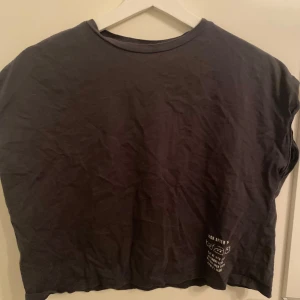 Grå t-shirt från H&M - Säljer en grå t-shirt från H&M i storlek 12-14 år tillsammans med ett par randiga byxor. Byxorna har ett litet hål ungefär under knät! Perfekt för en avslappnad stil.