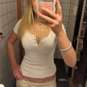 Vit urringad Tshirt med knappar - Säljer en vit urringad topp från Anna Field med korta ärmar och knappar framtill.