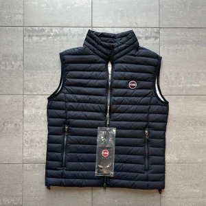 Colmar väst  - Snygg svart quiltad dunväst från Colmar med dragkedja och hög krage. Perfekt för lager-på-lager under kyliga dagar. Västen har två praktiska fickor med dragkedja framtill. Storlek 50 vilket motsvarar S. Modellen är 174 lång och väger 60 kg! Nypris är över 2300