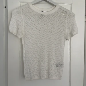 Vit stickad topp från H&M Divided - Vit, runt stickad topp från H&M Divided med ett snyggt mönster. Toppen har korta ärmar och en rund halsringning. Ganska gammal men inga defekter. Om du har frågor eller vill ha mer bilder kontakta mig🩷