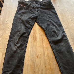 Svarta jeans från Diesel - Snygga svarta jeans från Diesel med klassisk femficksdesign och knappgylf. Perfekta för en stilren look. Märkesdetalj vid myntfickan ger en extra touch.