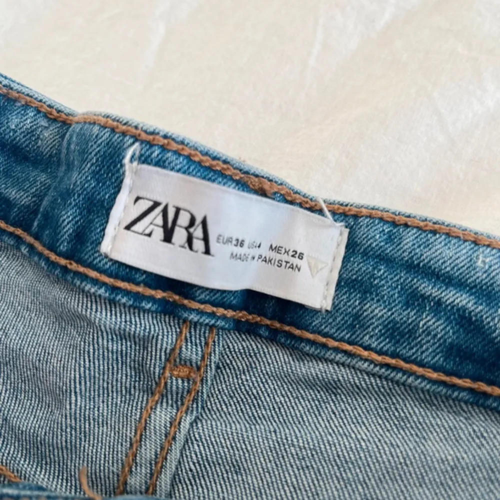 Säljer ett par snygga blå jeans från Zara. De är i en klassisk blå färg och har en cool slitsdetalj vid benslutet. Perfekta för en casual look och passar till det mesta. De är i storlek 36 och har en bekväm passform.. Jeans & Byxor.