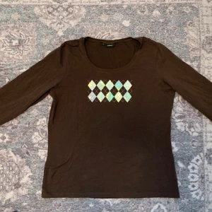 Rutmönstrad tröja  - En fin brun tröja med trekvartsärmar och argyle mönster.  Mönster har paljetter som man ser mer på bilderna ✨från Lindex i storlek L