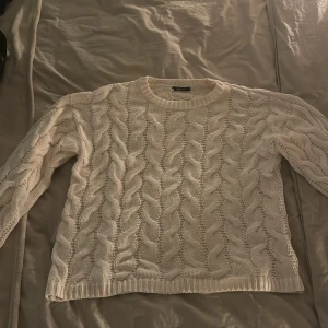 Vit stickad tröja från Gina Tricot - Säljer en superfin vit stickad tröja från Gina Tricot i storlek M. Den har ett snyggt flätmönster och är perfekt för både höst och vinter. Tröjan är långärmad och riktigt mysig att ha på sig. Perfekt för att hålla sig varm och stilren under kyliga dagar! ❄️