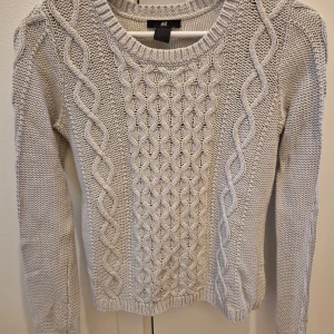 Stickad tröja HM - Kabelstickad tröja från HM. Använd några gånger. Lagom längd att ha utanpå eller innanför byxorna. Kan ha skjorta under eller bara som den är. 60% bomull, 40% akryl. Storlek XS. Sticks inte! Axelbredd 38 cm  längd 57 cm