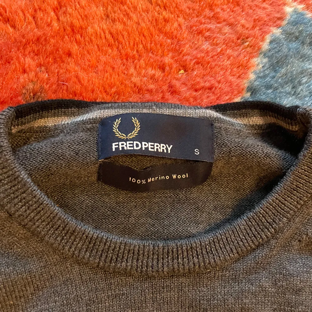  grå tröja från Fred Perry i 100% merinoull. Inga fläckar samt slitage förekommer. Måtten är följande:   Längd, ifrån toppen av axeln, ca 61 cm    bredd, armhåla till armhåla, ca 44cm  armlängd, ifrån armhåla utot, ca 48cm ärm öppning, ca 6cm. Tröjor & Koftor.