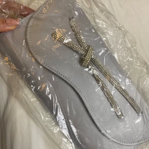 Väska fest - Handväska för fester/bröllop oanvänd i förpackning. Ingår en kedja i om man vill ha den som handväska med band. Silver färgad med diamanter på. Köpt i Dubai.