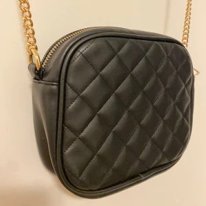 Svart läderväska med guldkedja - Svart läderväska med guldkedja