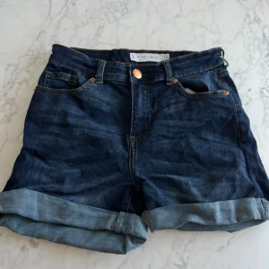Mörkblå jeansshorts från New Yorker - Säljer ett par snygga mörkblå jeansshorts från  New Yorker. De är högmidjade med klassisk fyrficksdesign och har uppvikta benslut. Perfekta för sommardagar eller en avslappnad vårlook. 🕶️