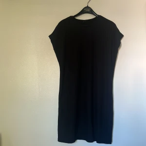 Svart och grön klänning från Gina Tricot - Säljer  snygga klänningar från Gina Tricot i storlek M. Den ena är .Klänningen har en enkel och stilren design med korta ärmar och en rak passform. Perfekta för både vardag och kontor ! 