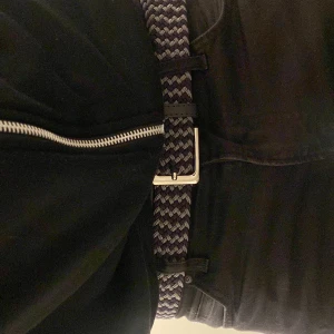 Flätat bälte - Flätat bälte i svart och grått. Ett perfekt bälte för en svart outfit för att göra outfiten mindre tråkig. Bältet passar perfekt till alla storlekar och jeans. 