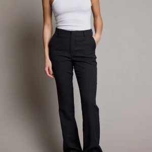 Svarta kostymbyxor - Säljer ett par stilrena svarta kostymbyxor som är perfekta för både vardag och fest. Byxorna har en hög midja och en bootcut-stil som ger en snygg siluett. De är gjorda i ett bekvämt material som passar bra till olika tillfällen.