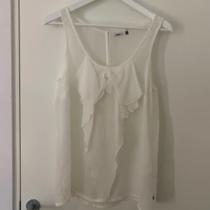 blus med tyg rosett 🎀 - en vit ärmlös blus med en tyg rosett, rosetten sitter ihop med blusen både uppe och nere. Har endast använt ett få tal gånger. blusen är genomskinlig. 🎀  skriv i dm om du har frågor eller vill ha flera bilder 💗 ps: pris kan diskuteras 