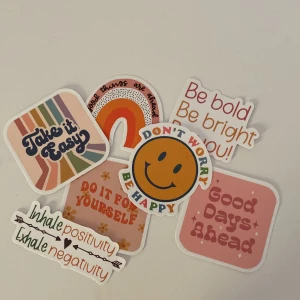  - Ett set med färgglada klistermärken med positiva budskap. De har olika former och färger, inklusive fyrkantiga och runda. Texterna inkluderar 'Take it Easy', 'Don't Worry Be Happy', 'Good Days Ahead', och fler. Perfekt för att dekorera anteckningsböc