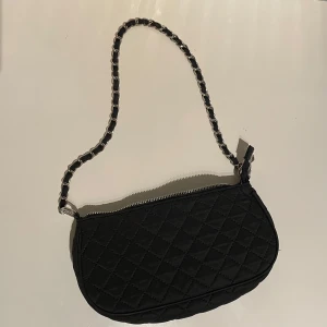 Handväska / axelväska med kedja  - Svart handväska med kedja. Använd och har tyvärr en liten fläck på ena sidan av väskan. 