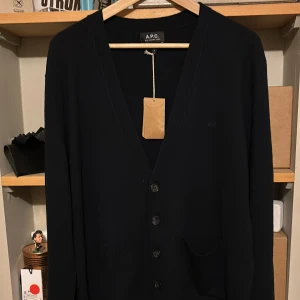 Marin blå kofta från A.P.C. - Säljer en stilren marin blå kofta från A.P.C. med knappar framtill. Den är helt ny och var bara lite lång för mig. Nypris ligger runt 3000kr