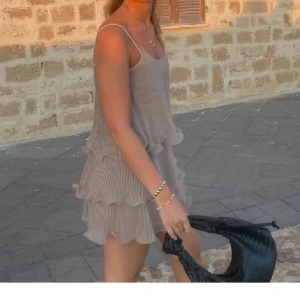 Beige kortklänning med volanger - Säljer en söt beige kortklänning med volanger. 