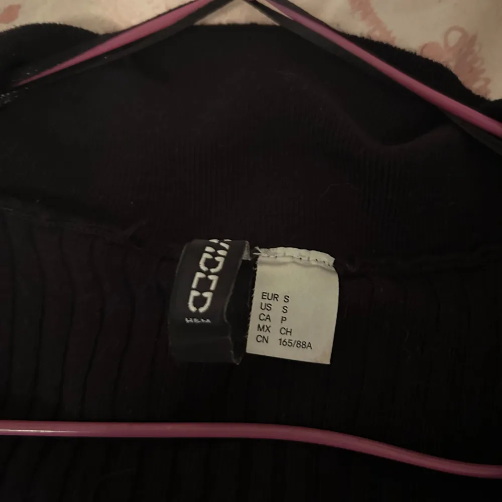 Snygg svart ribbad tröja från Zara med v-ringning och krage. Perfekt för en stilren look. Tröjan har långa ärmar och en figurnära passform. OBS den är kort i midjan. . Neuletakit & Villapaidat.