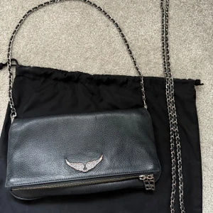 Svart axelväska från Zadig & Voltaire - Snygg svart axelväska i skinn från Zadig & Voltaire med dn kort och lång kedjeaxelrem. Bra skick men lite defekter på metallen som man kan se på bilderna💗💗