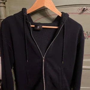 Marine blå zip hoodie från H&M S - Säljer en svart hoodie från H&M i loose fit. Den har dragkedja framtill och en bekväm huva med snörning. Perfekt för en avslappnad stil.