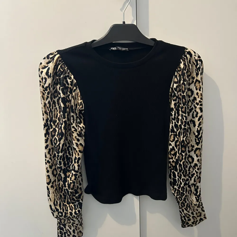 Säljer en cool svart topp från Zara med leopardmönstrade puffärmar. Toppen har en rund hals och är perfekt för att ge en trendig touch till din outfit. Ärmarna har knappar vid ärmsluten för extra stil. plus har aldrig använt denna så den är helt oanvänd 💕. Yläosat.