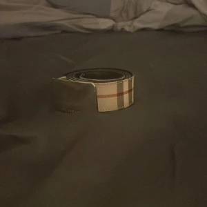 Burberry bälte - Snyggt burberry bälte med ett klassiskt rutigt mönster på utsidan och en stilren svart insida. Perfekt för att ge en touch av elegans till din outfit. Bältet har en modern design och passar till många olika stilar. Pris går att diskutera
