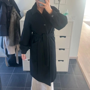 Svart kappa med bälte - Supersnygg kappa! Den är använd några gånger men är mycket gott skick! Jag är 162 cm, passar XS-S/M skulle jag säga. 