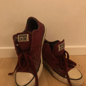 Vinröda Converse All Star sneakers - Säljer ett par vinröda Converse All Star sneakers med snörning. Skorna har en vit sula och den ikoniska logotypen på sidan. Perfekta för en avslappnad stil. Även svår att få tag på