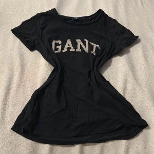 Svart t-shirt från GANT - Snygg svart t-shirt från GANT med stort tryck på framsidan. Perfekt för en casual look. Tillverkad i mjukt material för extra komfort.