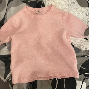 Rosa stickad tröja från Nelly - Säljer en söt rosa stickad tröja från Nelly. Tröjan har korta ärmar och en rund halsringning, perfekt för en avslappnad stil. Den är mjuk och bekväm att bära. Passar bra till både jeans och kjol. Det är i storlek XS men passar mig som bär storlek S
