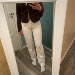 Vita 90-talsinspirerade jeans - Snygga vita jeans med en rak passform. De har en klassisk 90-talsstil och är perfekta för en trendig look. Midjemått är 27 och de har en knapp och dragkedja framtill. Längden är 32. Jag är 172 cm lång och bär storlek S 