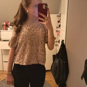 Beige blus från Holly & Whyte - Säljer en söt beige blus från Holly & Whyte med korta ärmar och ett vackert spetsmönster. Perfekt för att ge en romantisk touch till din outfit. Blusen har en lös passform och är tillverkad i ett mjukt material.