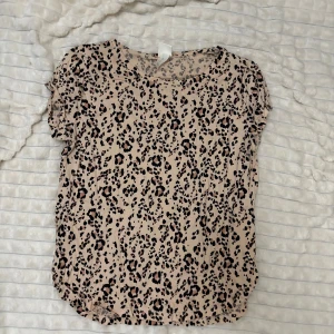 Beige leopardmönstrad topp - Säljer en beige topp med leopardmönster. Toppen har korta ärmar och en rund halsringning. 