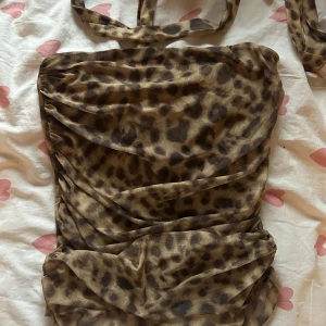 Leopardmönstrad topp - Säljer en snygg leopardmönstrad toppen med omlott-design och knytband. Toppen är axelbandslös och har en tight passform som framhäver figuren. 