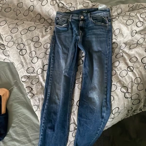 Blå jeans från Replay - Snygga blå jeans från Replay med en klassisk femficksdesign. De har en knappgylf och är perfekta för en avslappnad stil. Jeansen har en lätt tvättad look som ger dem en cool och trendig känsla.