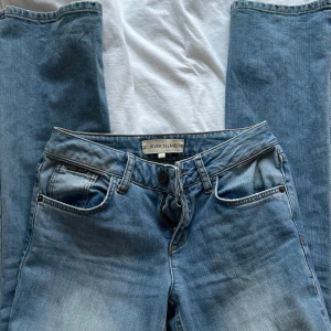 Low waist jeans från River Island - Snygga low waist blå jeans från River Island med en klassisk femficksdesign. De har en knappgylf och är i en ljusblå tvätt som ger en avslappnad look. Perfekta för en casual stil.