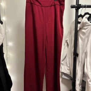 Vinröda kostymbyxor - Snygga vinröda byxor med hög midja och dragkedja i sidan. lite smånoppriga på ett ställe!